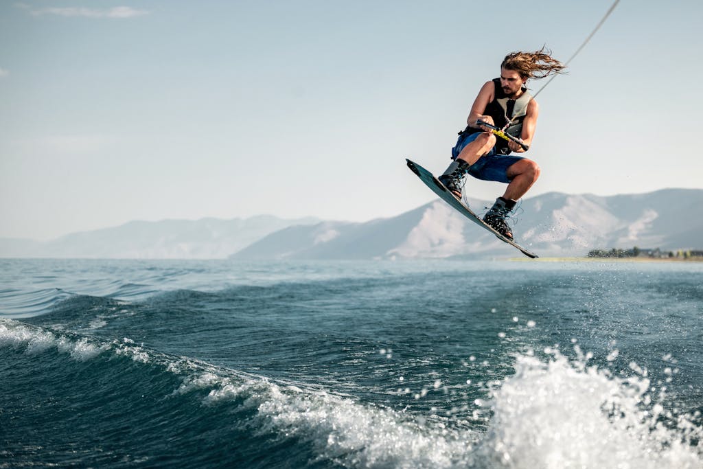 A young man executes a high jump on a wakeboard over the ocean waves, showcasing extreme water sports skill.