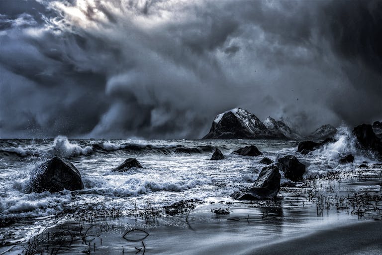 Powerful waves crash on Nordland, Norway shore under dramatic storm clouds.