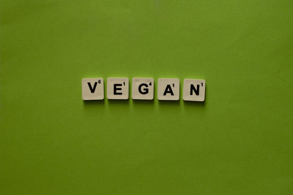Vegan concept illustrated with letter tiles arranged on a vibrant green background.
